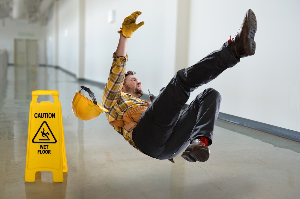 A construction worker slips and falls on a wet floor